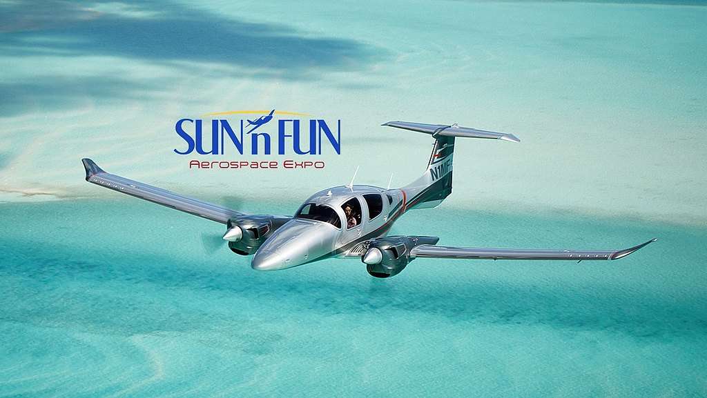 A sleek DA62 silver aircraft glides gracefully over turquoise waters, showcasing the beauty of flight and the surrounding landscape.