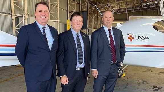 Three men standing next to a DA40 XLT in a hangar. 