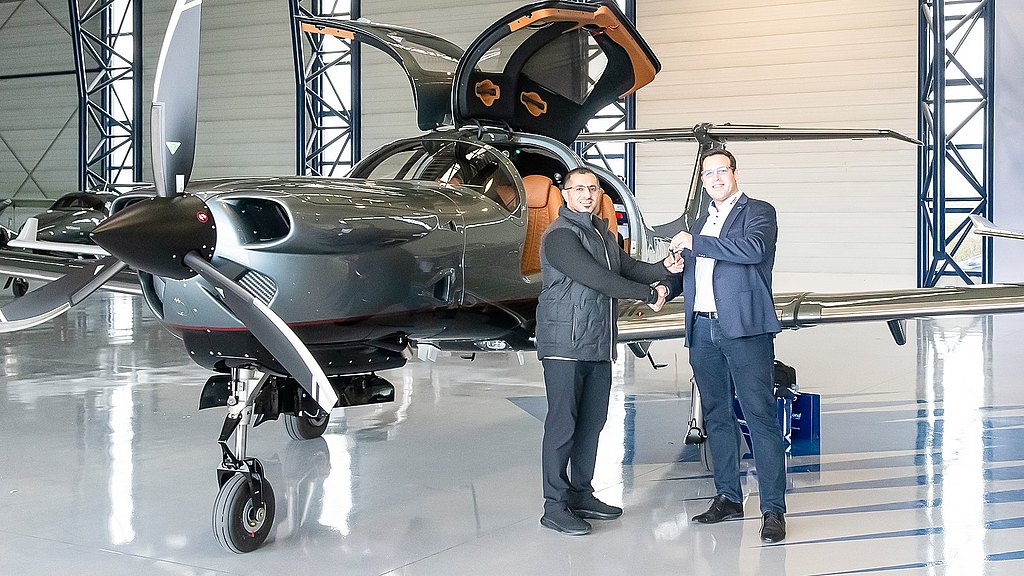 2 men shaking hands infront of a DA50 RG in the hangar.