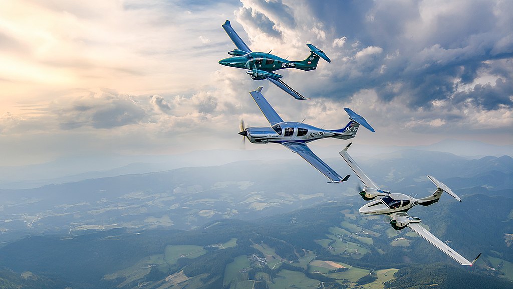 Three Diamond aircraft soar gracefully through a cloudy sky, showcasing their aerodynamic designs against a stunning landscape.