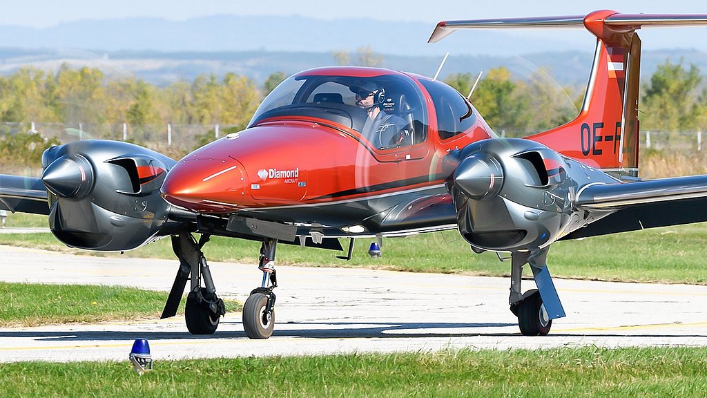 Orange DA42-VI taxiing on the apron.