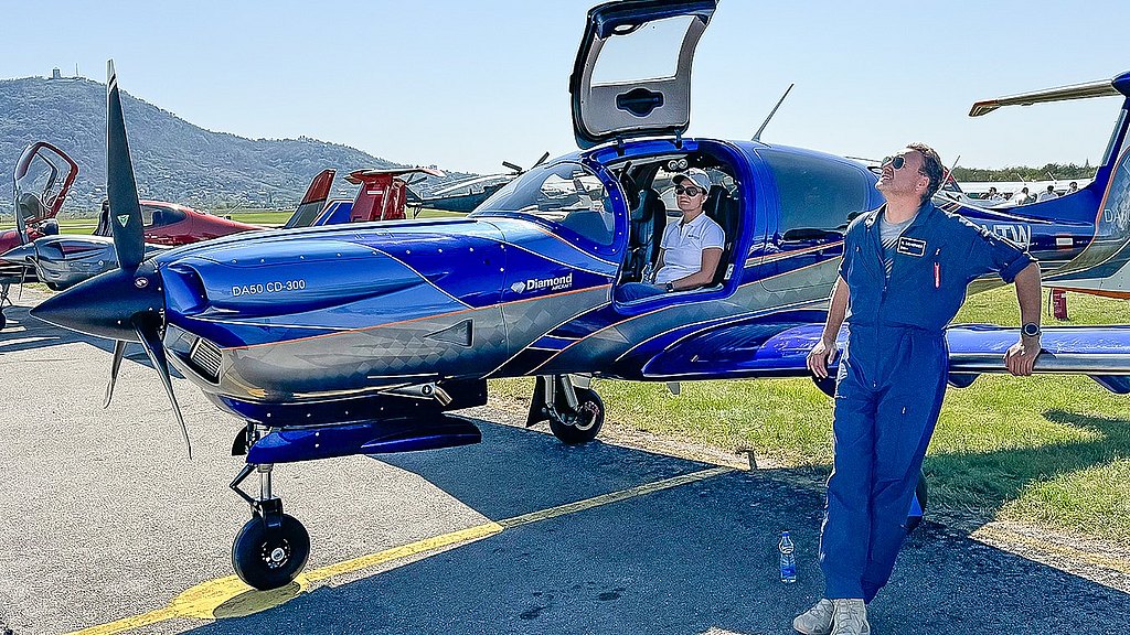 Pilot leaning on the wing of a DA50 RG and looking into the sky. 