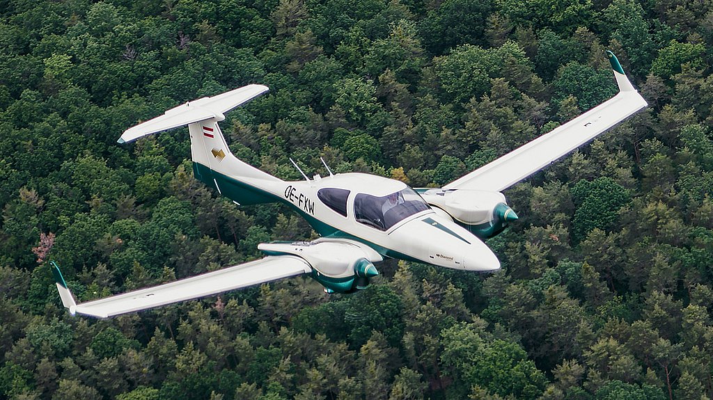 DA42-VI flying over green forrest.