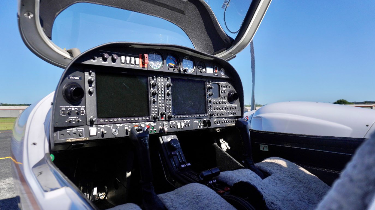The cockpit of a DA42-VI aircraft features multiple screens, controls, and instruments, showcasing a modern aviation environment.