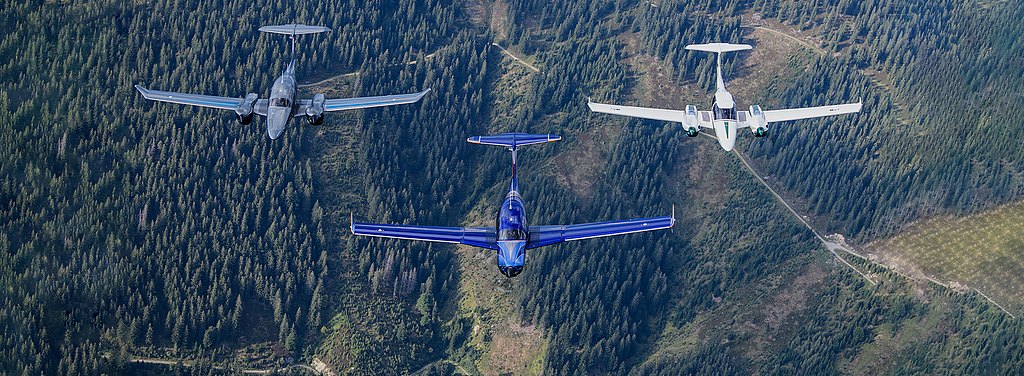 A DA50 RG, DA62 and DA42-VI flying in formation over a forrest.
