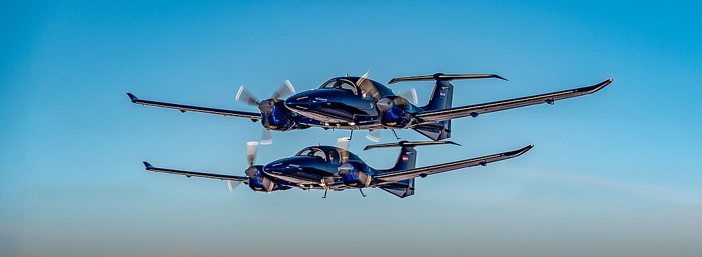 Two blue DA62 aircraft flying in formation. 