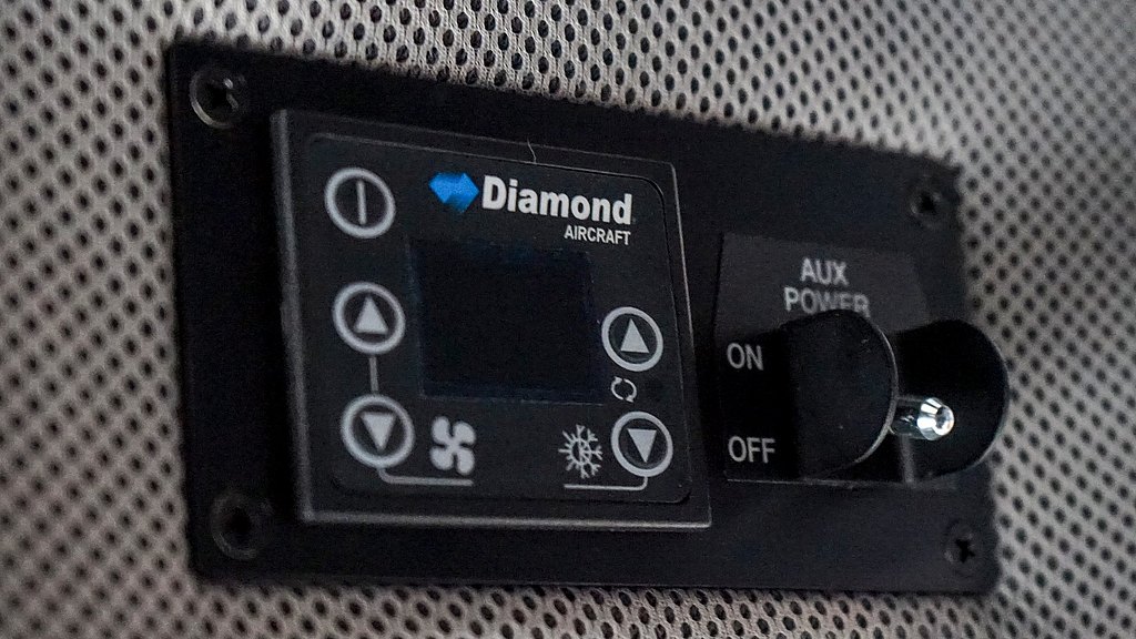 Detailed view of an aircraft's air conditioning control panel, showcasing buttons for fan speed and power options, set against a mesh background.