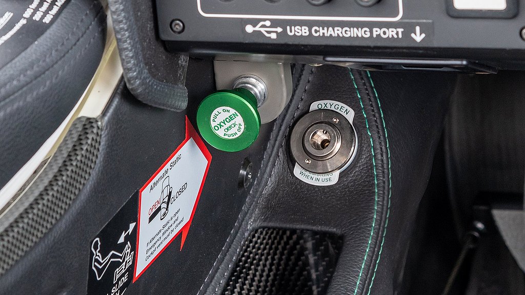 A close-up view of an aircraft's oxygen control panel, featuring a green pull knob and safety labels for operation.