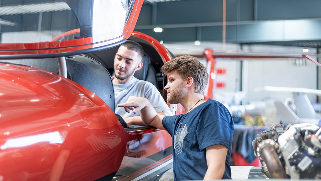 Two apprentices working on a cockpit of a DA42-VI.