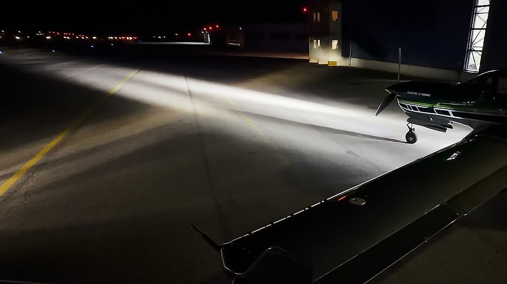 DA50RG-LED-landing-taxi-lights The image features a DA50 RG aircraft on a runway at night, with powerful LED taxi and landing lights illuminating the area and creating dramatic contrasts.