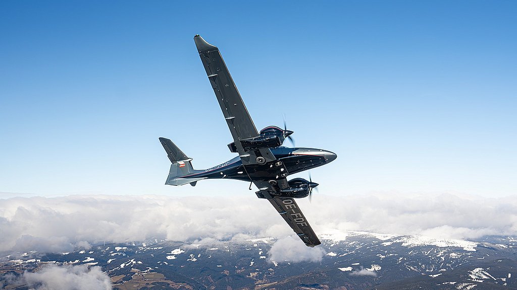 A sleek aircraft performs a sharp turn against a backdrop of blue sky and fluffy white clouds, showcasing its aerodynamic design.