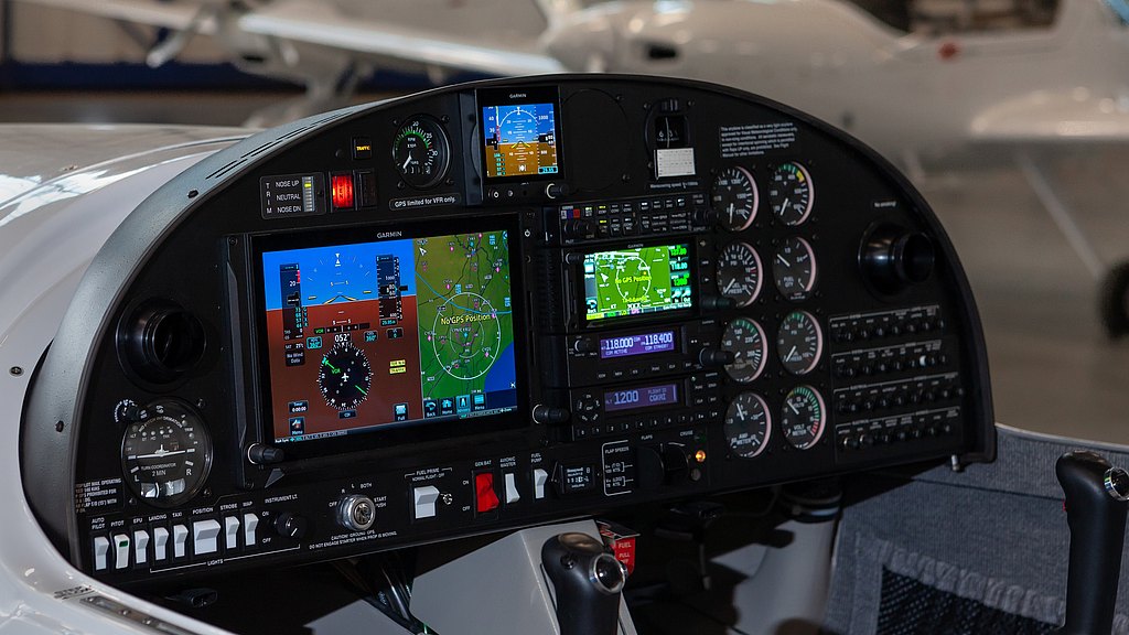 The cockpit of a DA20 aircraft features multiple digital displays and gauges, showcasing flight data and navigation information.