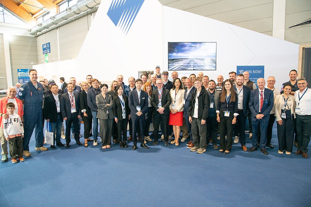 A diverse group of professionals gathers at an event, smiling and posing together in a modern exhibition space.