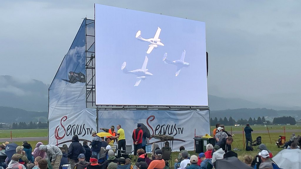 Diamond formation on a large outdoor display on the airfield with people watching.