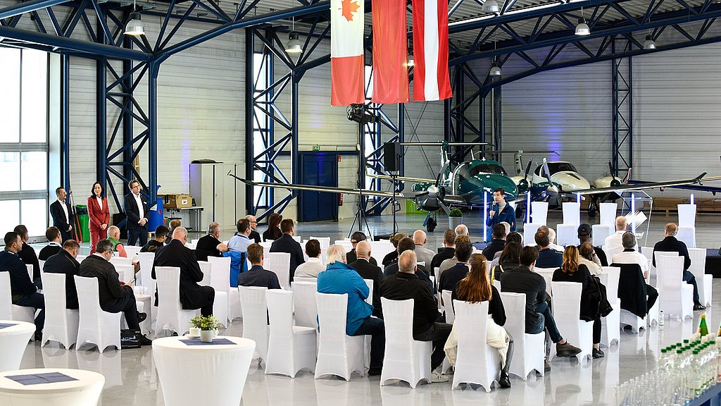 Audience listening to speaker in a hanger.