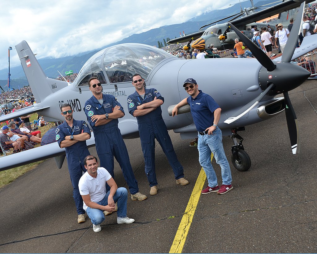 Men standing infront of DART aircraft on static display with crowd in the background.