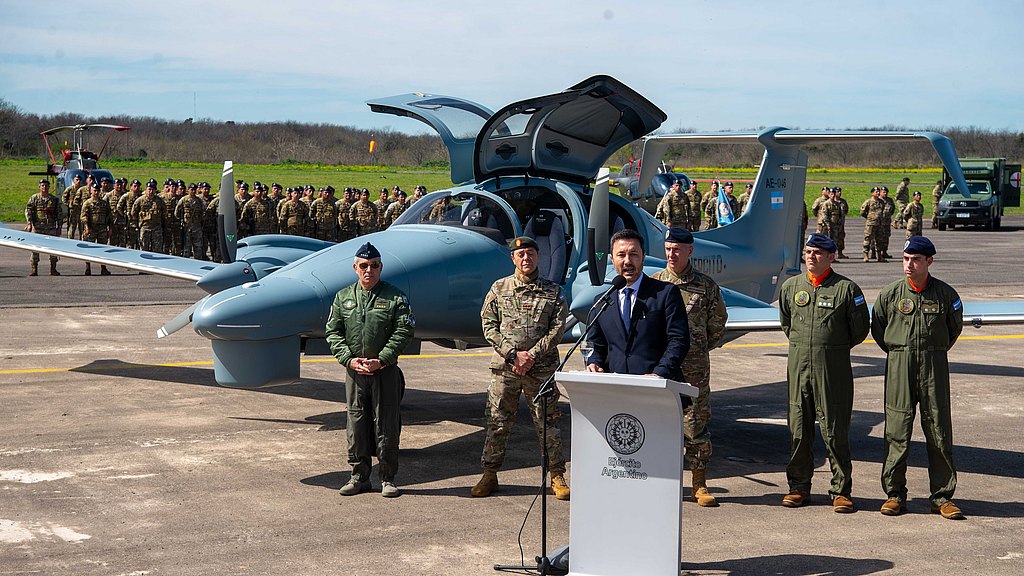 Man staning behind a lectern with army officials and DA62 MPP in the background.