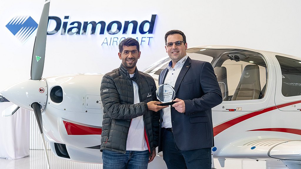 Sama Aviation and Diamond Aircraft employee holding an award in front of a DA40 NG.