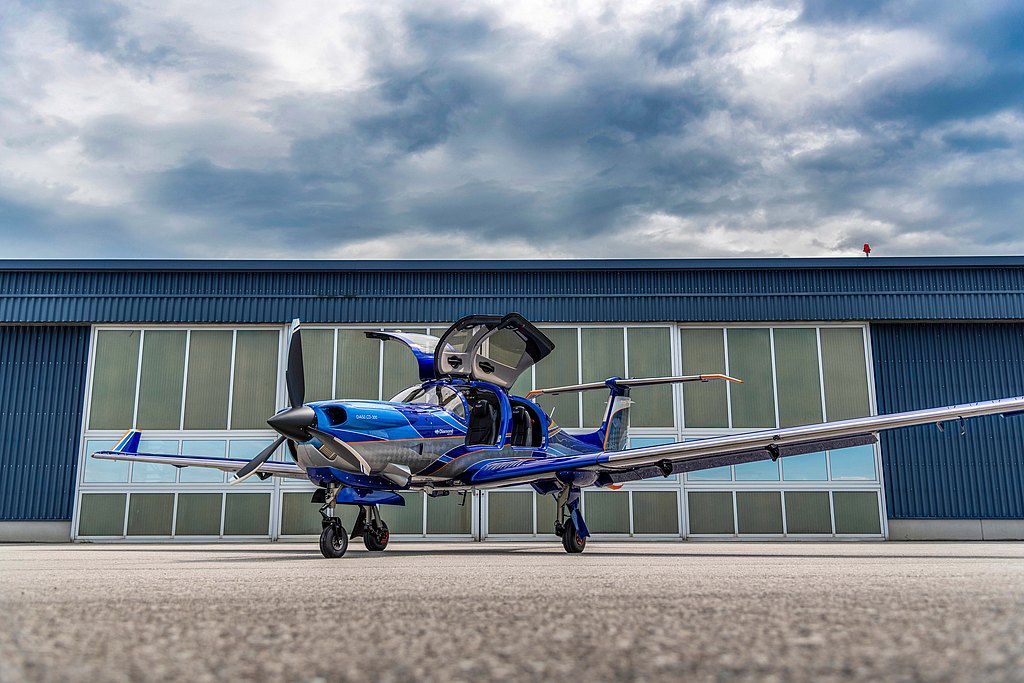 DA50 RG with open gullwing doors standing in front of a hangar.