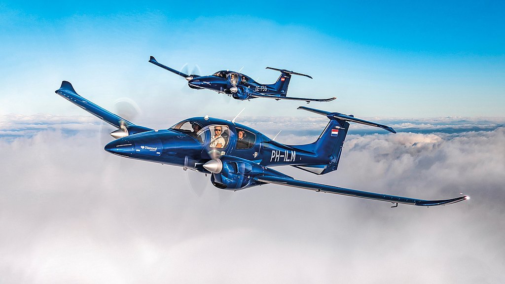 Two blue DA62 flying in formation over clouds in blue skies