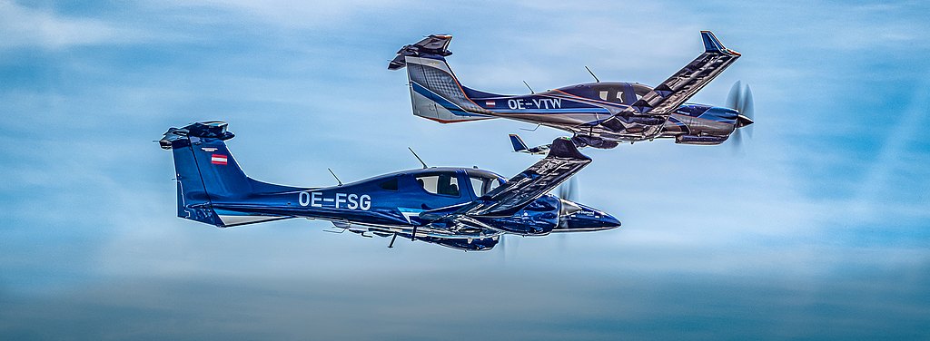 A blue DA62 and DA50 RG soaring in blue skies. 